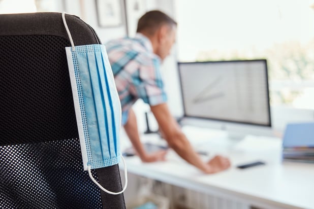 Employee back at work with mask on chair